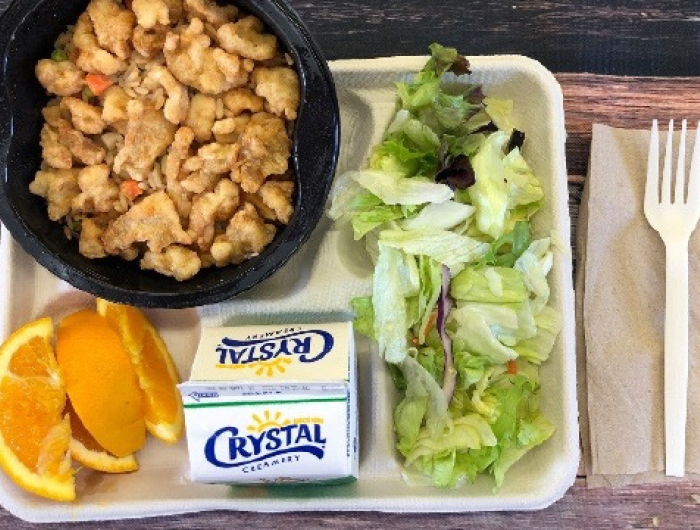 A lunch tray: teriyaki chicken and rice, orange slices, salad, milk